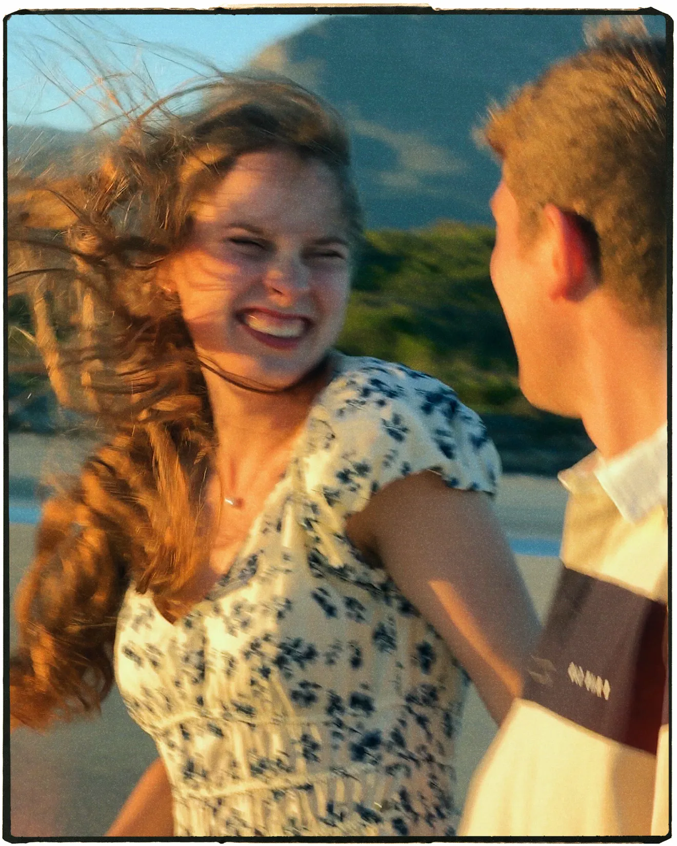 A bride laughing on the beach in a floral dress