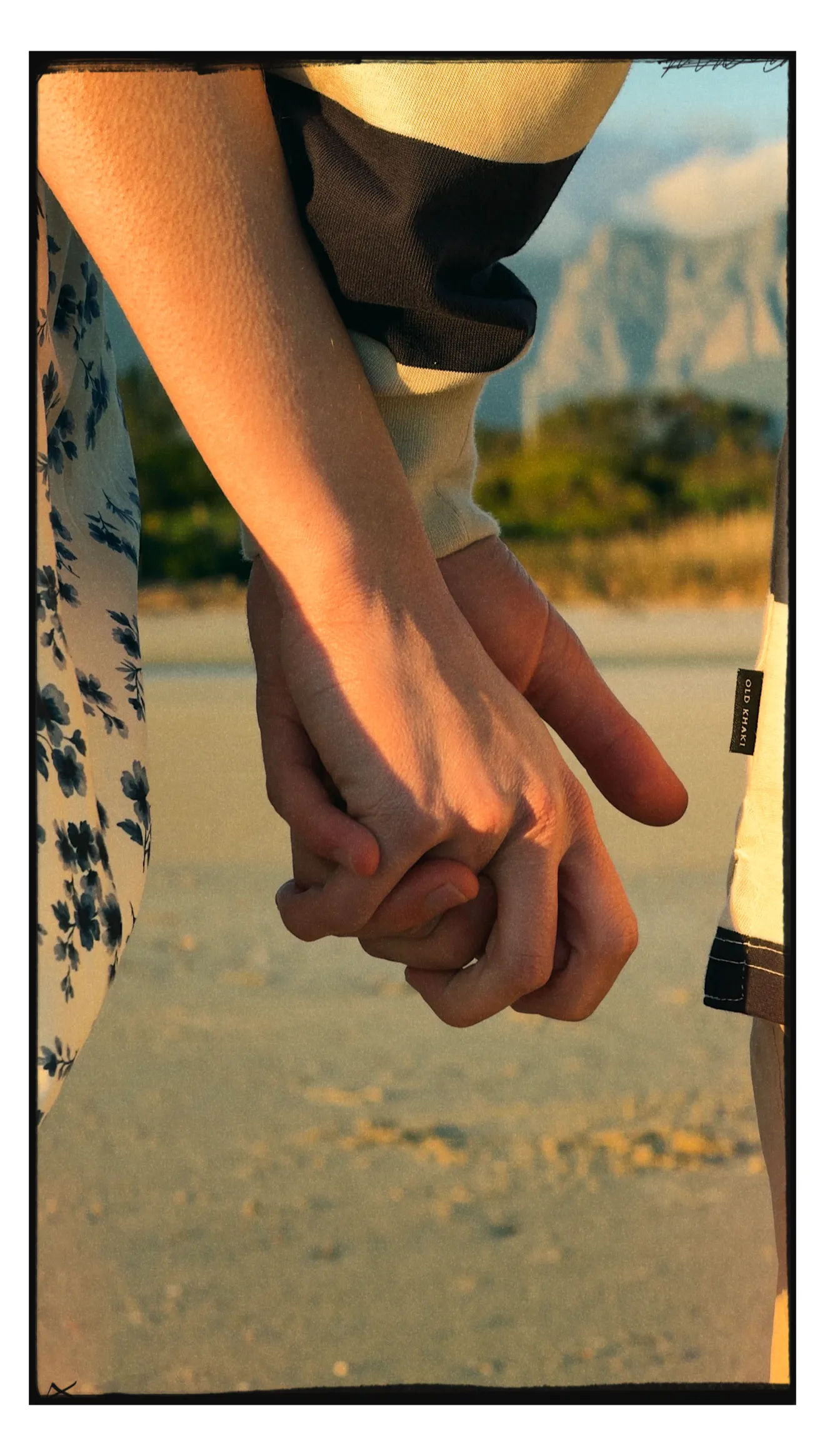Two hands held on the beach at golden hour