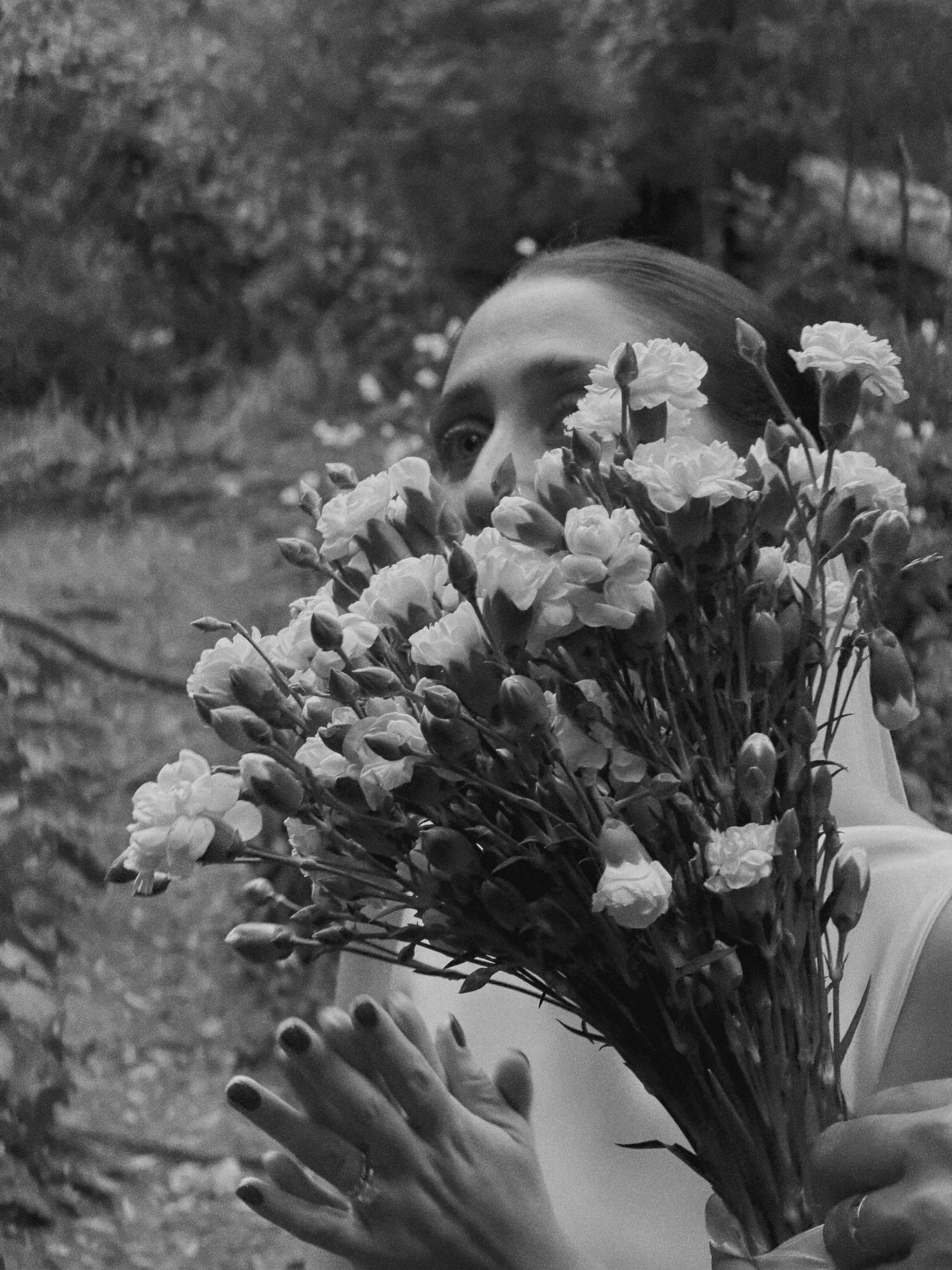 A black and white portrait behind a bouquet